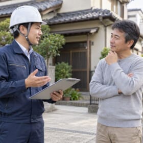 住宅の前で解体工事の現地調査について相談するイメージ
